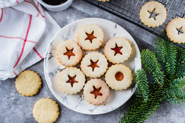 Christmas Linzer cookies with raspberry jam on concrete table background. Traditional Austrian biscuits filled. Top view and copy space