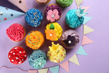 Delicious cupcakes with party decor on color background