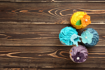 Delicious colorful cupcakes on wooden background