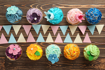 Delicious colorful cupcakes with party decor on wooden background