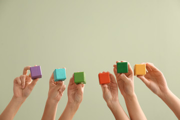 Young women holding cubes on color background