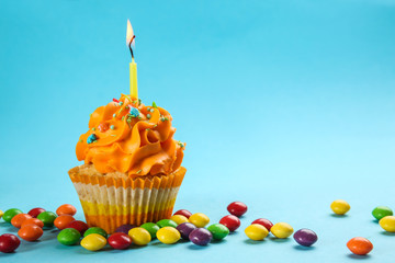 Tasty birthday cupcake with burning candle on color background