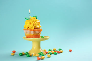 Tasty birthday cupcake with burning candle on color background