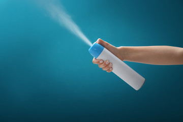 Woman spraying air freshener on color background