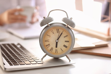 Alarm clock with laptop on light table in office