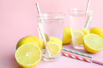 Glasses of water with lemon on color background