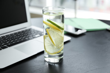 Glass of water with citrus fruits on dark table