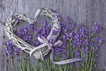 Lavender flowers  with wicker heart on wooden background 