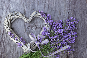 Obraz premium Lawenda kwitnie z łozinowym sercem na drewnianym tle