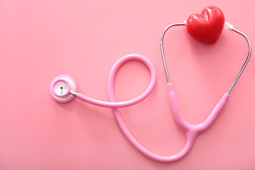 Medical stethoscope with red heart on color background. Health concept