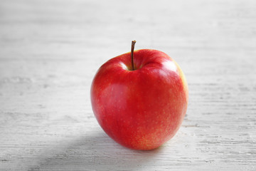 Ripe tasty apple on light wooden table