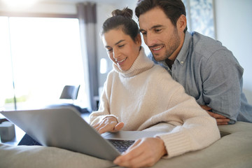 Fototapeta premium Gorgeous couple looking at computer at home