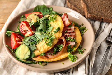 Tasty omelet with bacon and vegetables on plate