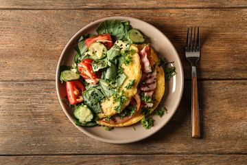 Tasty omelet with bacon and vegetables on plate