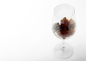 Glass with coffee ice cubes on white background
