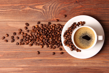 Cup of aromatic coffee and coffee beans on wooden background. Top view. Coffee drink