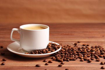 Cup of aromatic coffee and coffee beans on a wooden background.