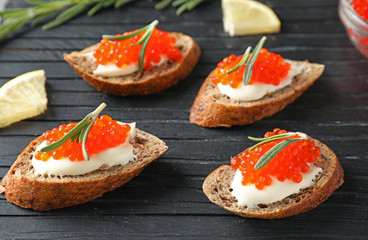 Delicious sandwiches with red caviar on wooden board, closeup