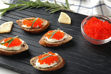 Delicious sandwiches with red caviar on wooden board