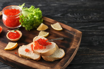 Bread with delicious red caviar and jar on wooden board