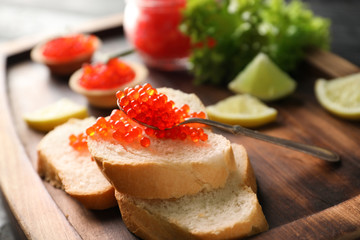 Bread with delicious red caviar on wooden board, closeup