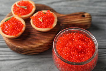 Jar with delicious red caviar on wooden table