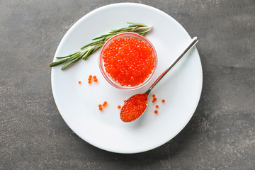Bowl and spoon with delicious red caviar on plate
