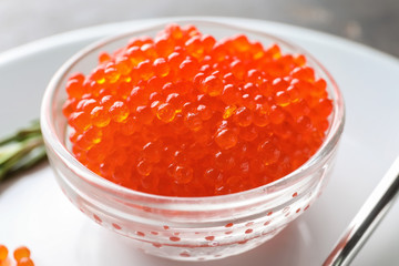 Bowl with delicious red caviar on plate, closeup