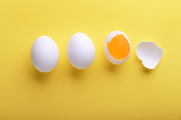 Cracked and whole chicken eggs on color background