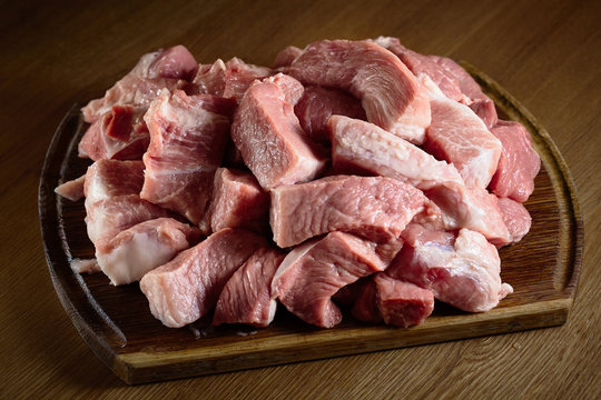 Raw pork on cutting board befor meat grinder. Fresh pig meat steak slices on wooden oak cut board prepared for grinder background close-up