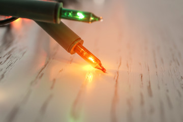 Glowing Christmas lights on table, closeup