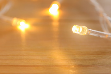 Glowing Christmas lights on table, closeup