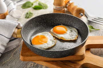 Pan with tasty fried eggs on wooden boards