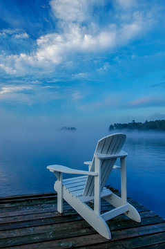 white deck chair on the dock, overlooking mist covered lake