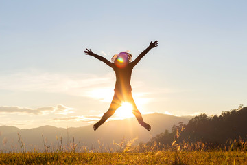 Silhouette of happy child jumping playing on mountain at sunset time