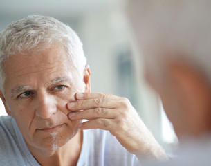mature man in front of mirror using cosmetics