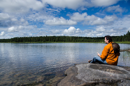 man sitting on rocks near a lake