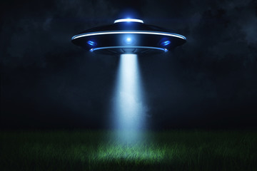 3d rendering of a UFO at night with a beam of light coming out of the hatch and lighting a landing point in the green grass. © gearstd