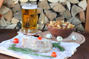 Fototapeta na wymiar Chunks of pork on the parchment, light beer mug on the background of firewood.