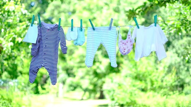 Baby clothes on clothesline drying in garden. Newborn childhood concept