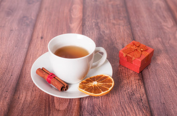 Cup of tea with gift box on wooden background