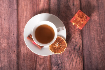 Cup of tea with gift box on wooden background