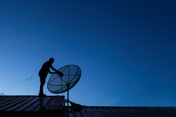 Silhouette of young man technicians are installing satellite dish 