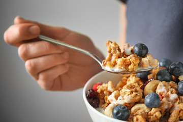 Woman eating tasty granola with blueberries, closeup