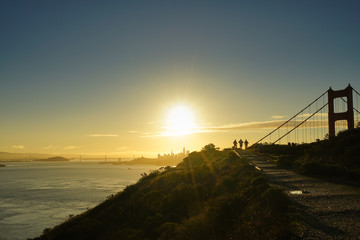 Joggers near Golden Gate Bridge just after sunrise, with the sun shining above San Francisco...