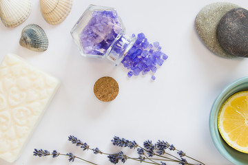 Obraz na płótnie Canvas Flowers of lavender, white soap, decorative bottles, lemon, sea salts, seastones and seashells on a white background.