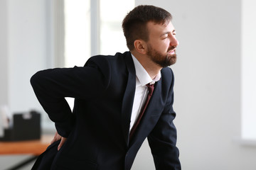 Businessman suffering from back pain in office