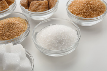 Bowls with different kinds of sugar on white background