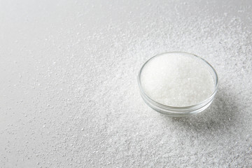 Bowl with granulated sugar on light background