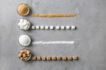 Bowls with different kinds of sugar on grey background